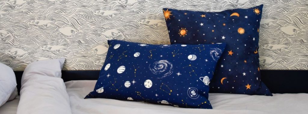 Tejut világűr dekorvászon világítós, tengerkék színű alapon bolygókkal és galaxisokkal - melyek világítanak a sötétben. A csillagok és csillagképek színe melegsárga. díszpárna
